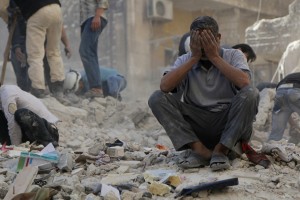 A man reacts amid debris after what activists said were explosive barrels thrown by forces loyal to Syria's President Assad in Al-Shaar neighbourhood of Aleppo